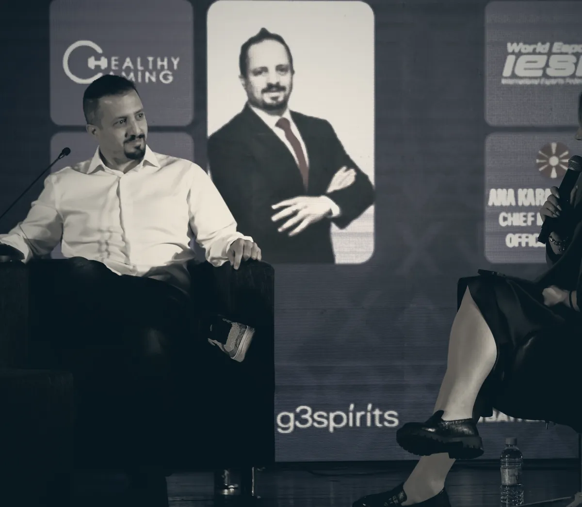 Mostafa Abusamra on a panel, the HealthyGaming mark on the screen behind him.
